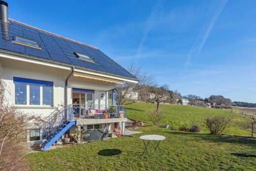view of property featuring a lawn, roof mounted solar panels, and a wooden deck