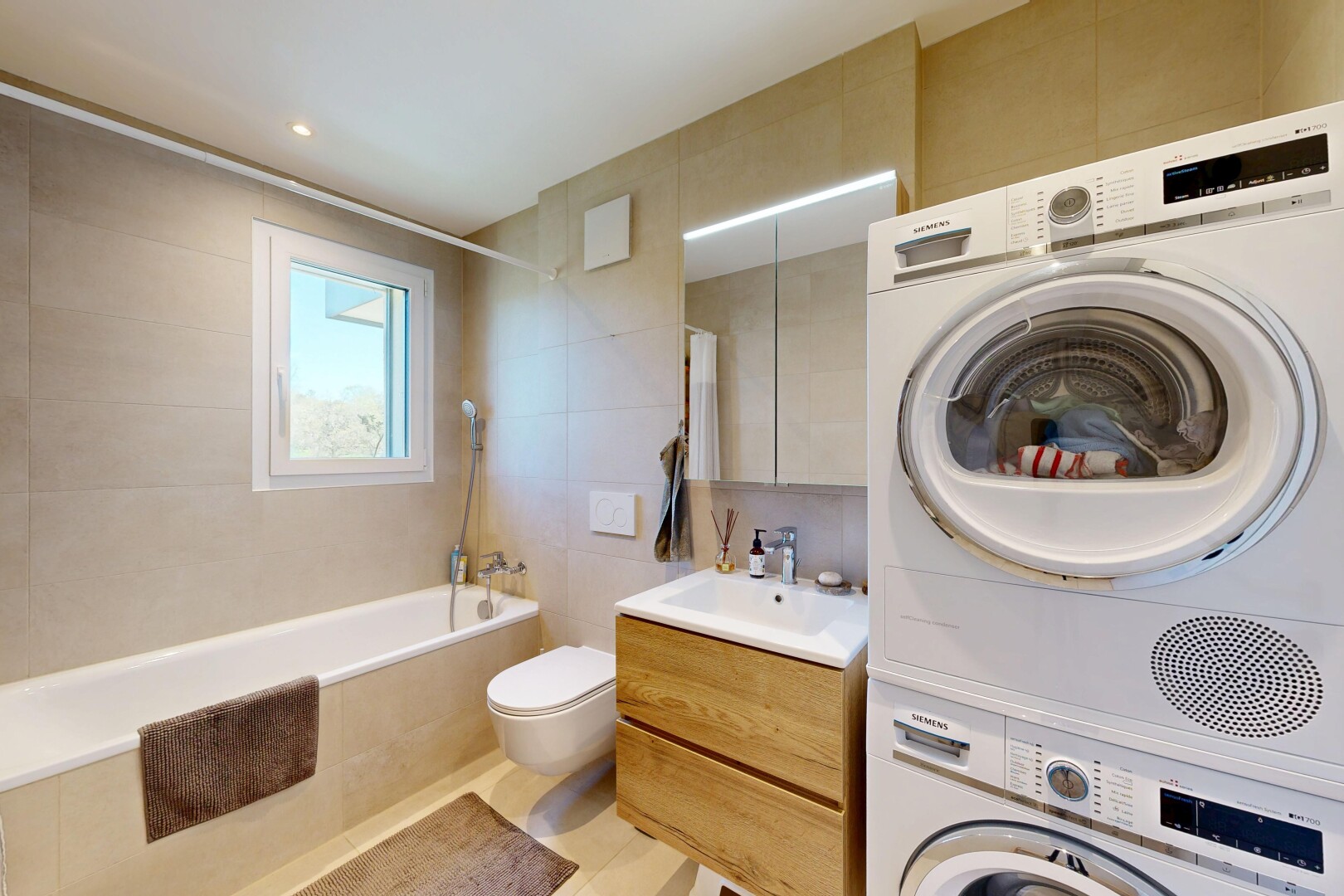 salle de bains avec tile wall, mur en carrelage, miroir, lavabo (ou coiffeuse selon le contexte), et salle de bain complète