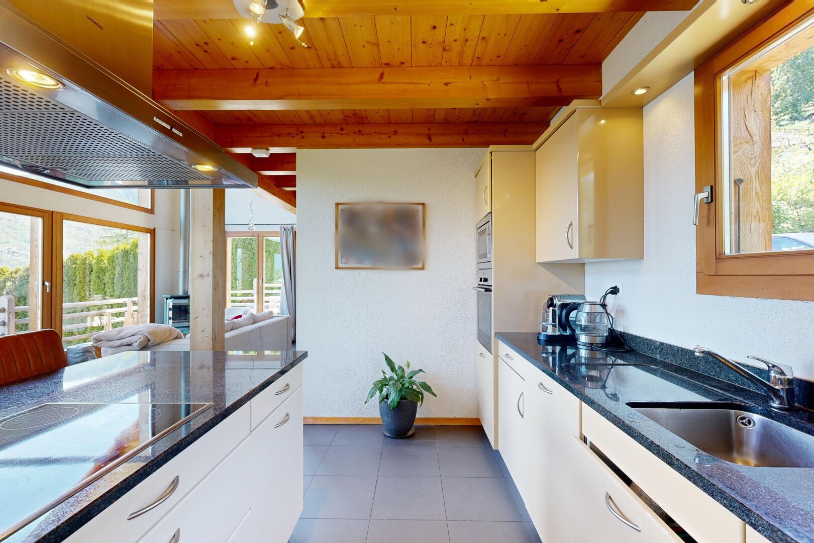 cuisine avec dark countertops, hotte, lumière naturelle, natural light, et armoires blanches