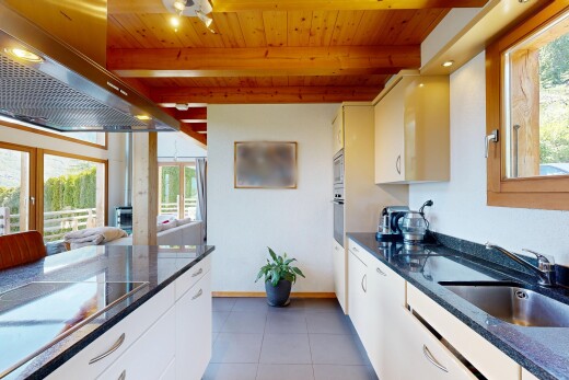 cuisine avec dark countertops, hotte, lumière naturelle, natural light, et armoires blanches