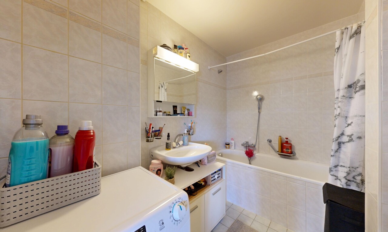 salle de bains avec tile wall, mur en carrelage, lave-linge et sèche-linge, inside property, et lavabo (ou coiffeuse selon le contexte)