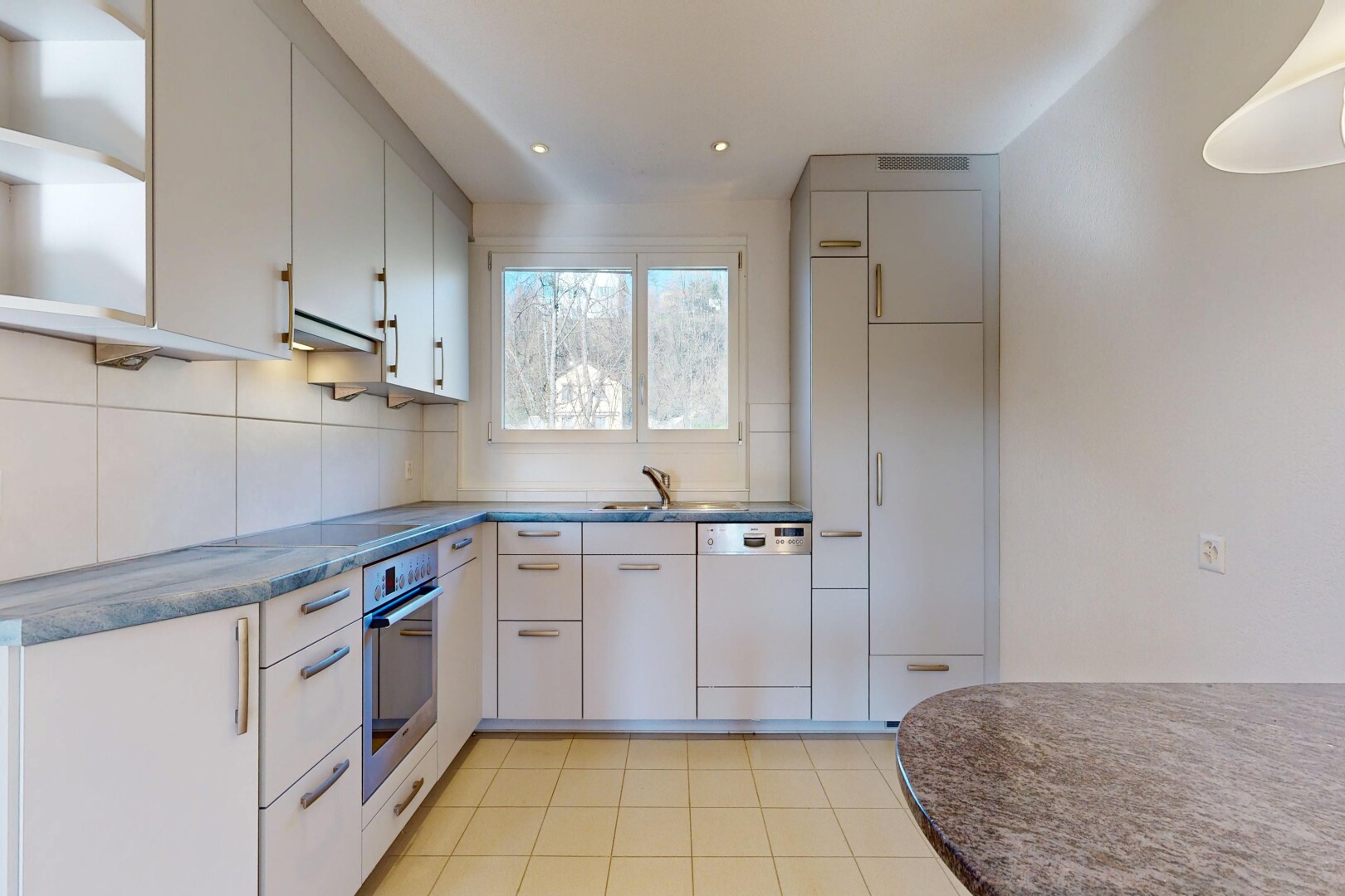 cuisine avec curved countertops, light floor, lave-vaisselle, dark countertops, et plans de travail