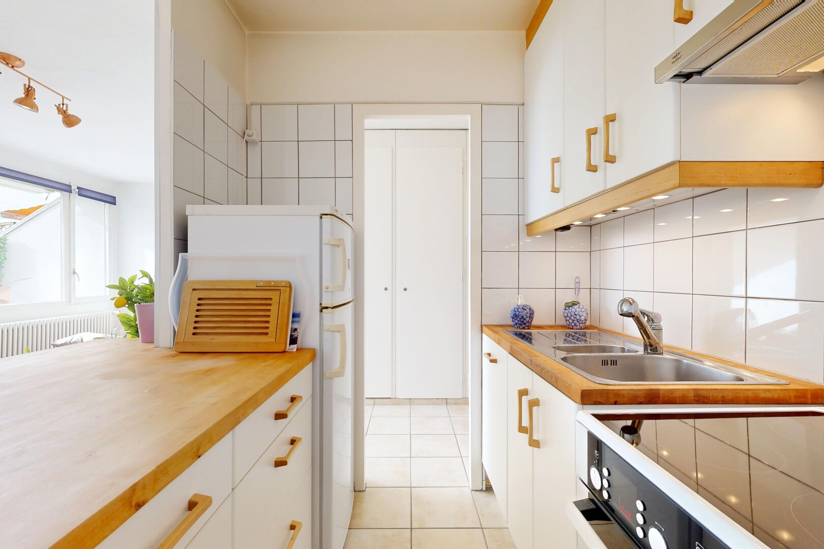 cuisine avec armoires blanches, inside property, hotte, backsplash, et dosseret