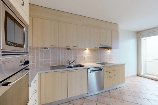 cuisine avec armoires marron clair, micro-ondes, armoires à panneau plat, backsplash, et natural light