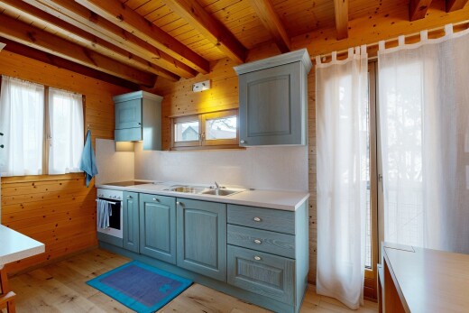 kitchen featuring light countertops, light wood-style floors, oven, a wood ceiling with exposed beams, and black electric cooktop