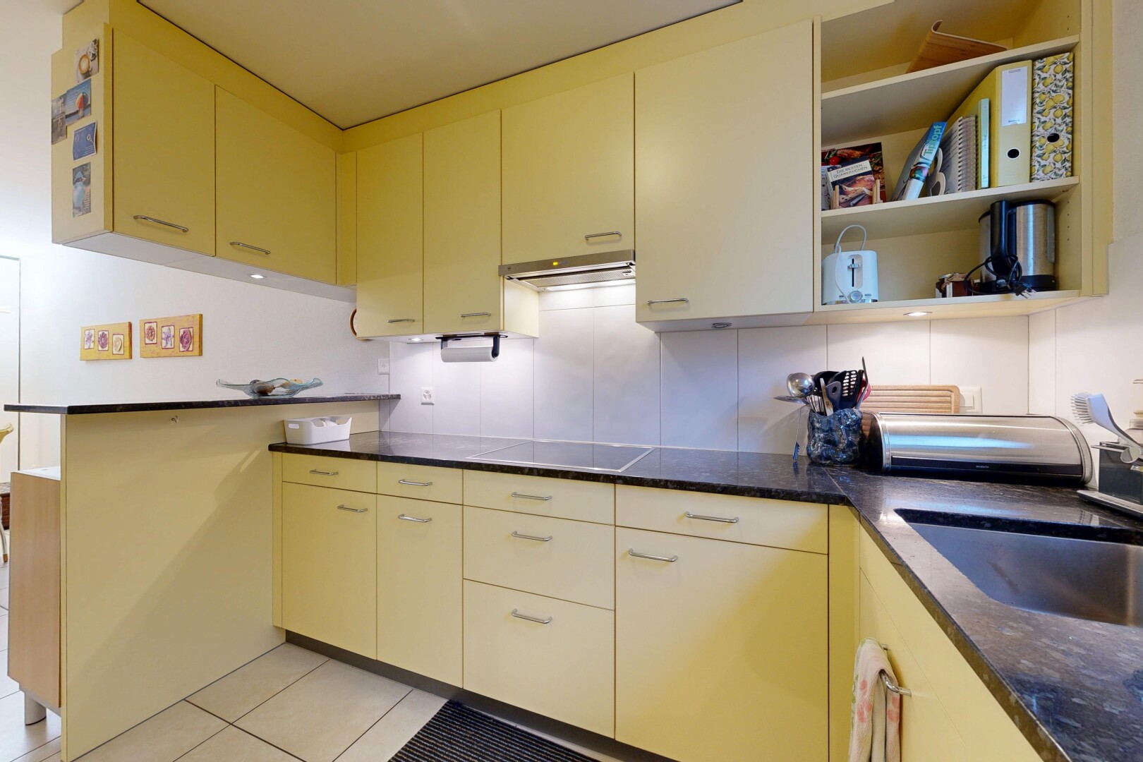cuisine avec dark countertops, péninsule de cuisine, kitchen peninsula, évier, et tile floor
