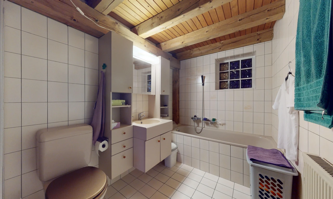 salle de bains avec mur carrelé, vasque, poutres apparentes, carrelage, et baignoire