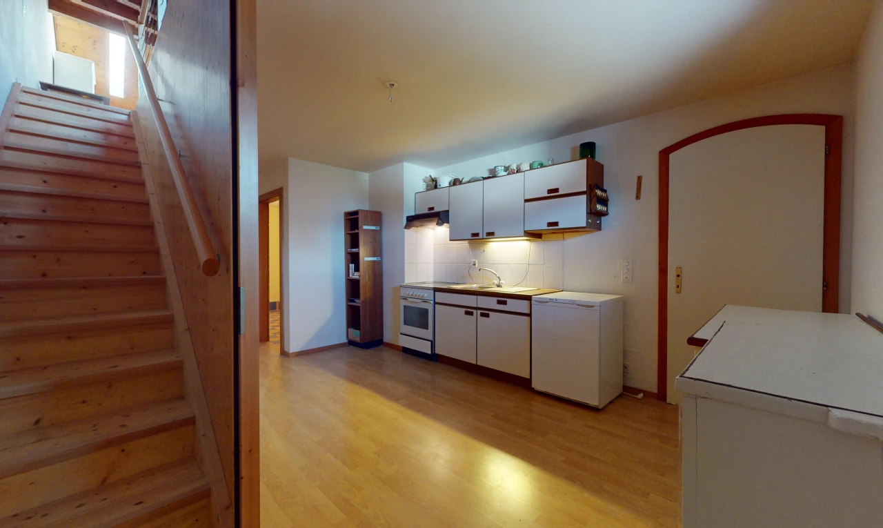 cuisine avec meubles blancs, réfrigérateur, et plancher de bois
