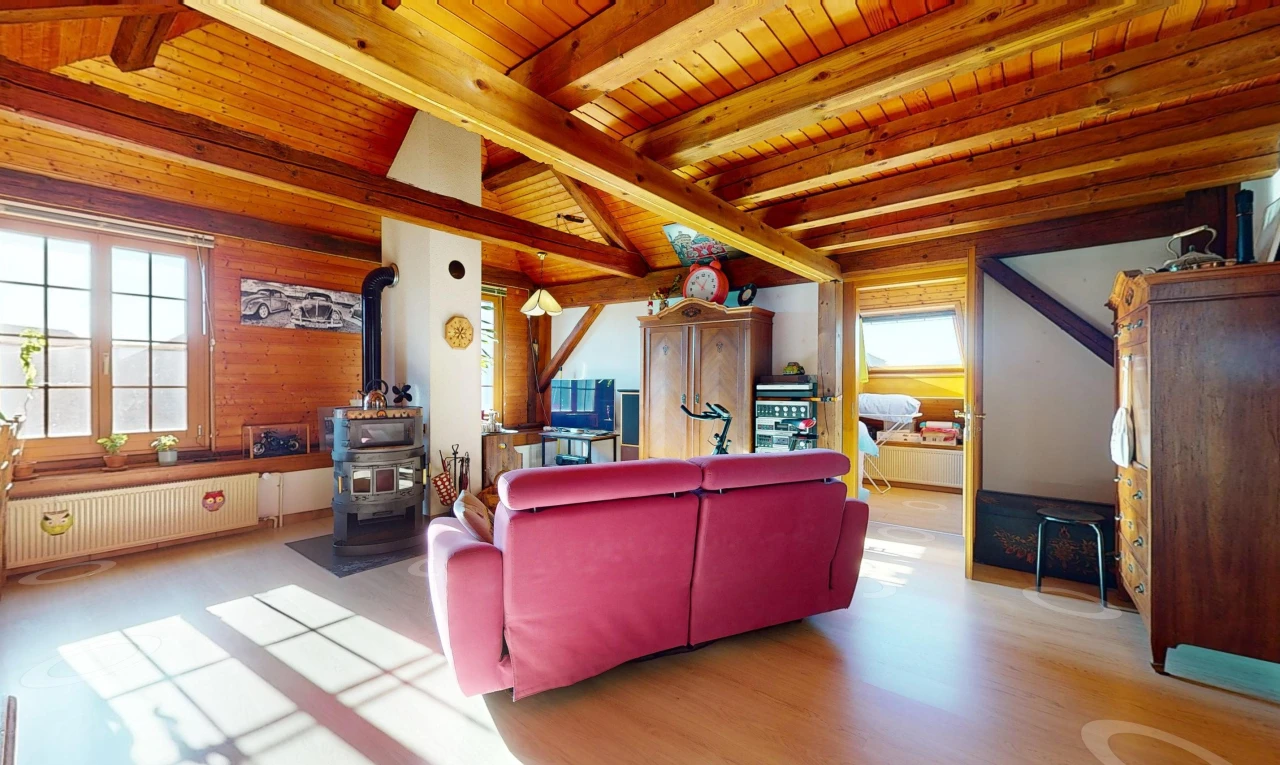 salon avec radiateur, poutres apparentes, plafond de bois, lumière naturelle, et poêle à bois
