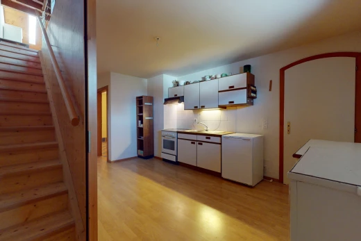 cuisine avec meubles blancs, réfrigérateur, et plancher de bois