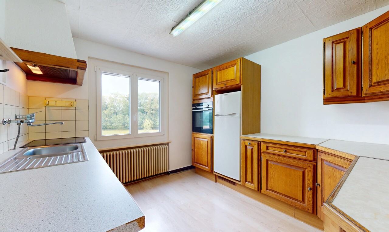 cuisine avec armoires marron moyen, radiateur, armoires élevées, réfrigérateur, et wood finish floor