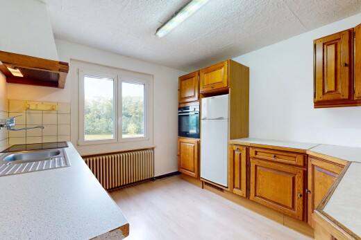 cuisine avec armoires marron moyen, radiateur, armoires élevées, réfrigérateur, et wood finish floor