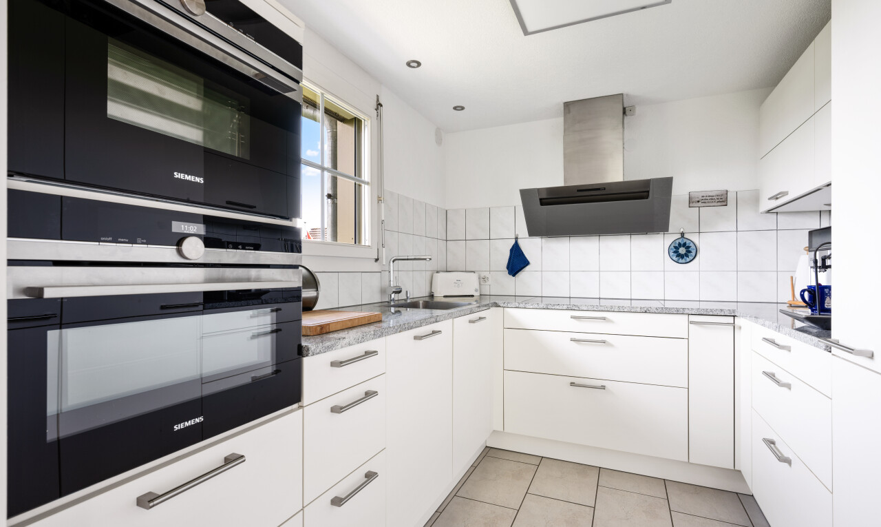 cuisine avec dosseret, backsplash, hotte, light floor, et lumière naturelle