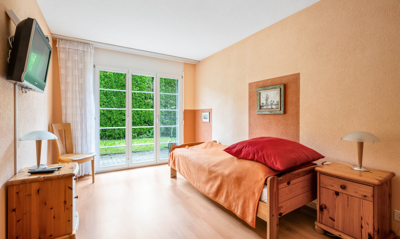 zimmer / schlafzimmer mit holzfußboden, wood finish floor, außenzugang, fernseher, und natürliches licht