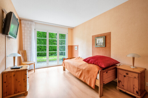 zimmer / schlafzimmer mit holzfußboden, wood finish floor, außenzugang, fernseher, und natürliches licht