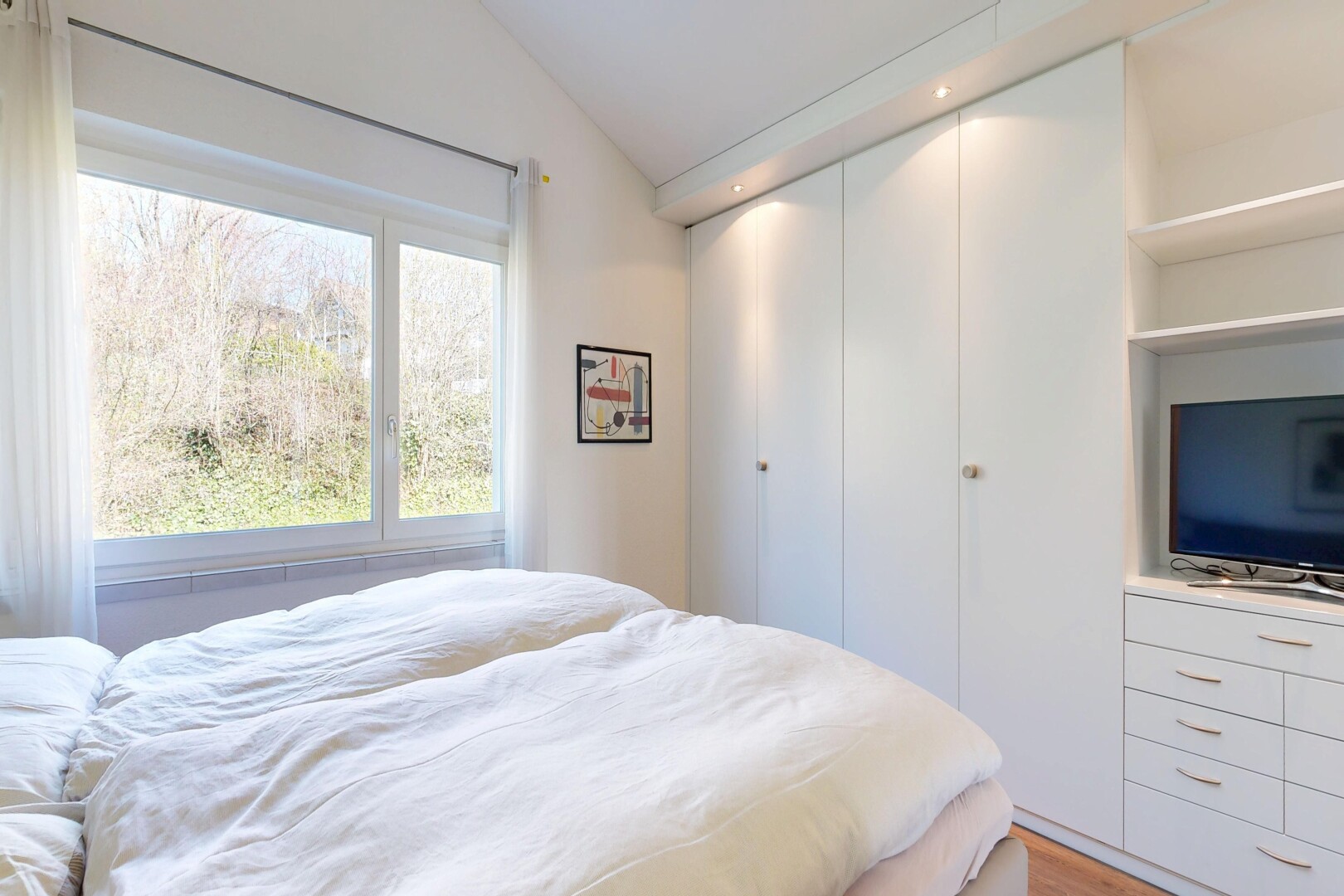 chambre avec télévision, inside property, sol en finition bois, wood finish floor, et plafond voûté