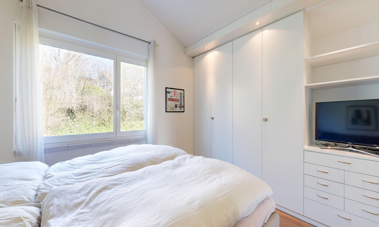 chambre avec télévision, inside property, sol en finition bois, wood finish floor, et plafond voûté