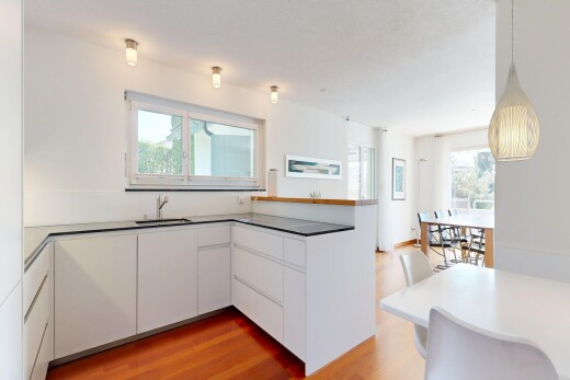 cuisine avec two heights countertops, armoires blanches, white cabinets, sol en finition bois, et wood finish floor