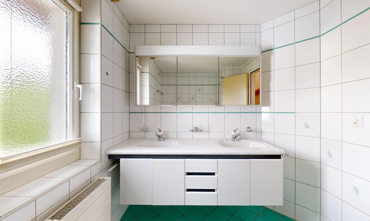 full bath with double vanity, healthy amount of natural light, and tile walls