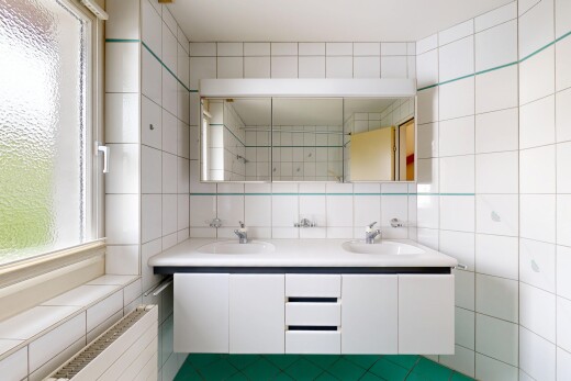 full bath with double vanity, healthy amount of natural light, and tile walls
