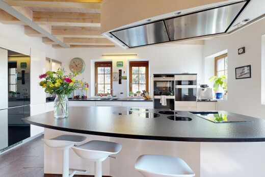 kitchen with double wall oven, dark countertops, range hood, and plenty of natural light