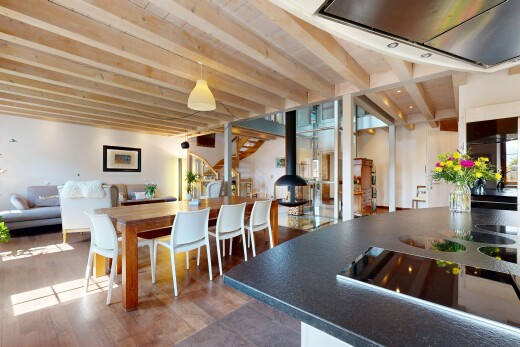 wohn- / esszimmer mit holzfußboden, gipskartonwand, balkendecke, und holzofen