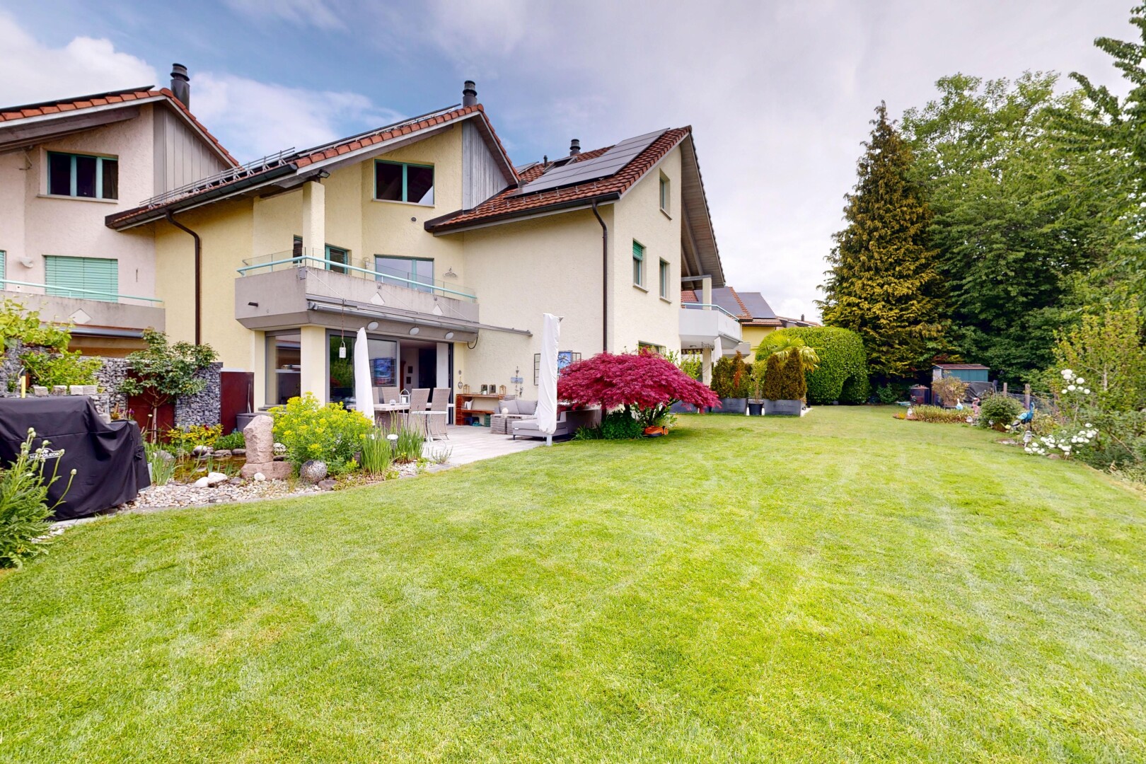 außenansicht mit balkon, solaranlage, from property, rasen, und stuckverkleidung