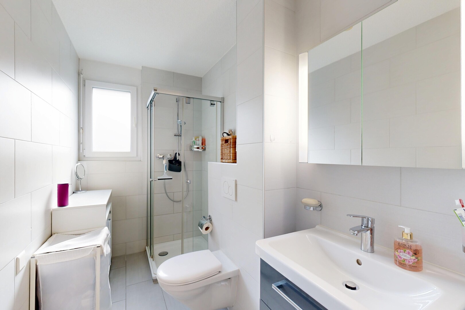 salle de bains avec mur en carrelage, tile wall, lavabo (ou coiffeuse selon le contexte), lumière naturelle, et natural light