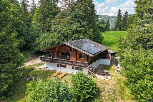 view of home with a forest view, a deck, stairway, solar panels, and a patio