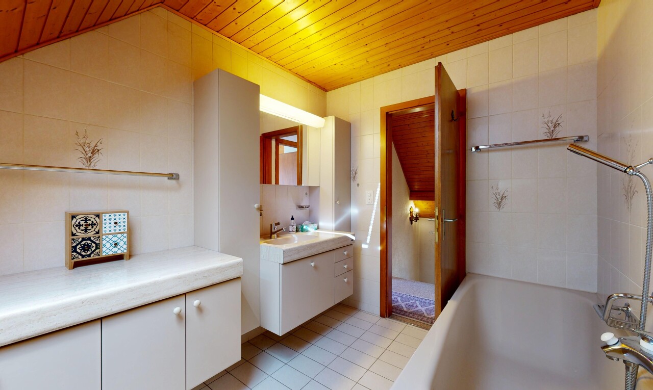 salle de bains avec plafond en bois, wood ceiling, lavabo (ou coiffeuse selon le contexte), miroir, et bain