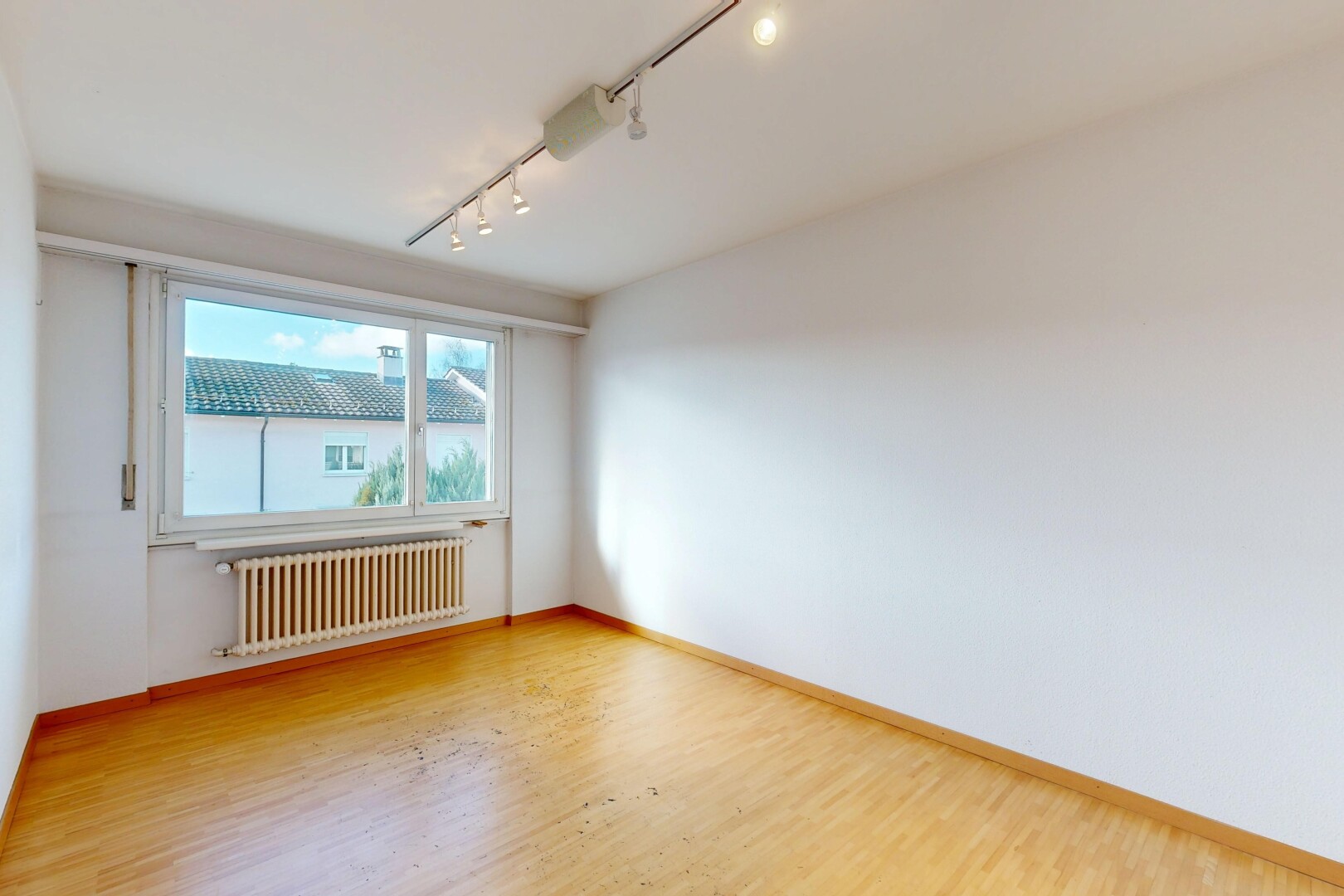 pièce vide avec track lighting, éclairage sur rail, radiateur, wood finish floor, et sol en finition bois