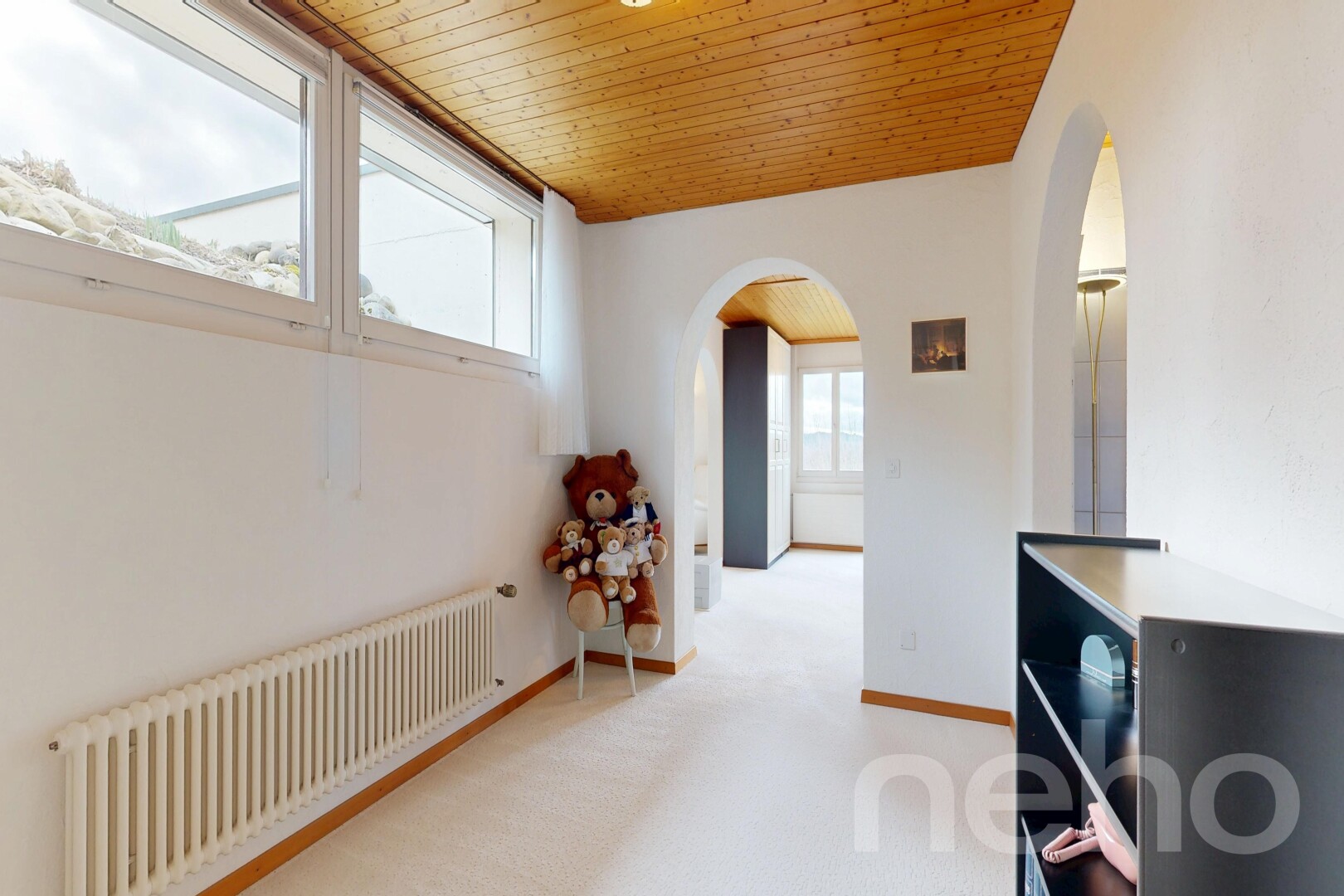 hallway with radiator, wood ceiling, light colored carpet, and arched walkways