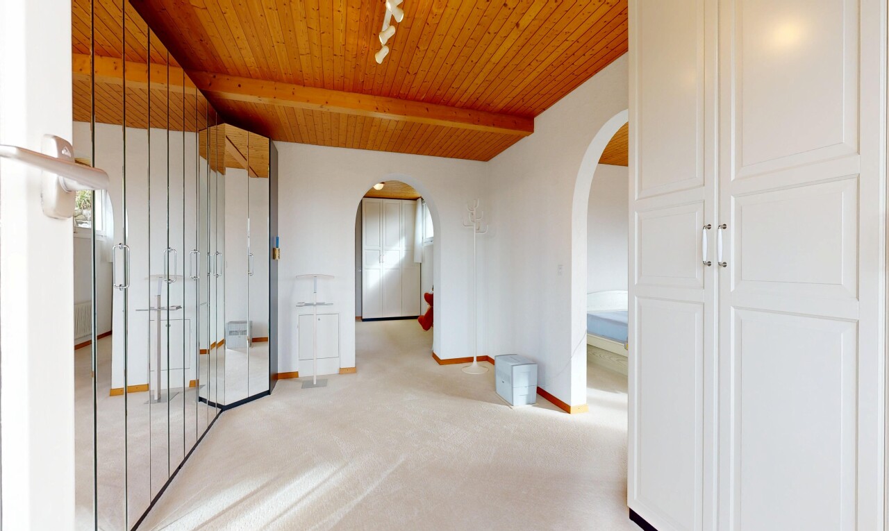 hall featuring rail lighting, a wood ceiling with exposed beams, light carpet, and arched walkways