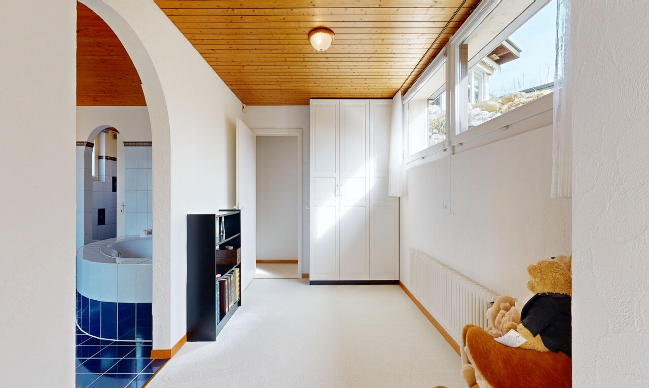 hall featuring arched walkways, wooden ceiling, and light colored carpet