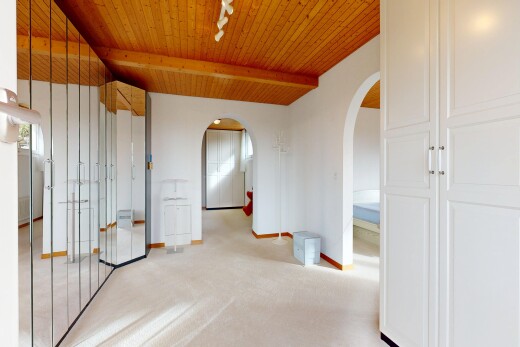 hall featuring rail lighting, a wood ceiling with exposed beams, light carpet, and arched walkways