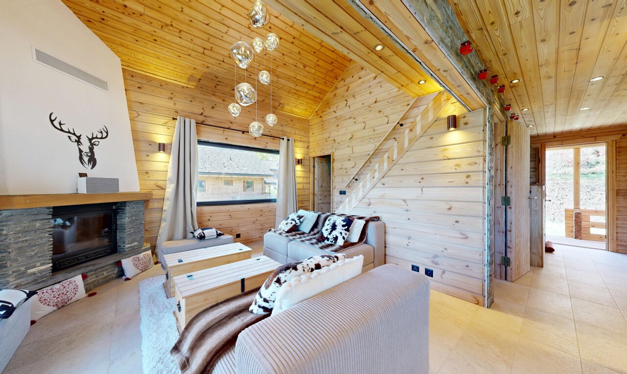 living room with a vaulted wooden ceiling, wooden walls, a stone fireplace, and plenty of natural light