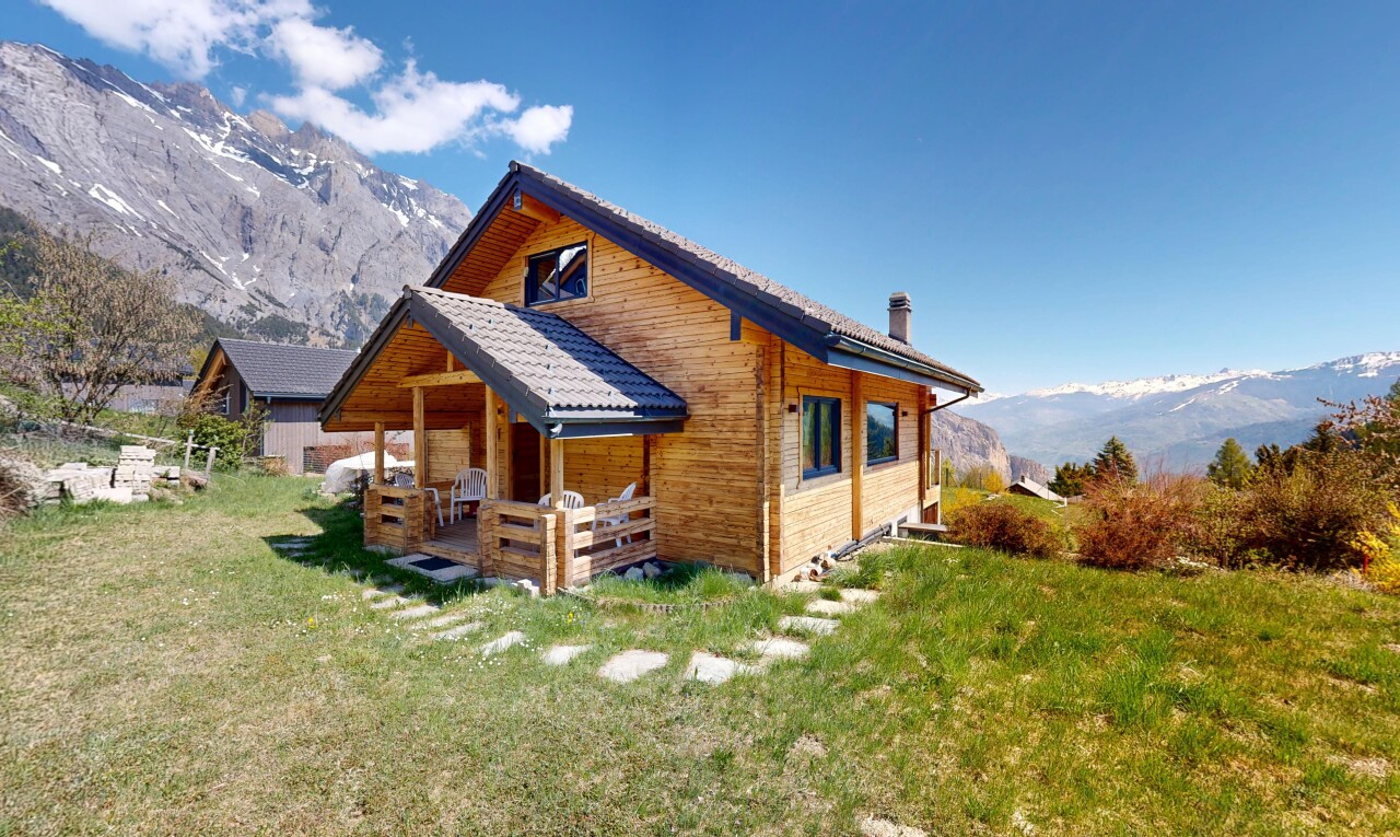 outdoor house with a mountain view, a chimney, a lawn, and a patio area