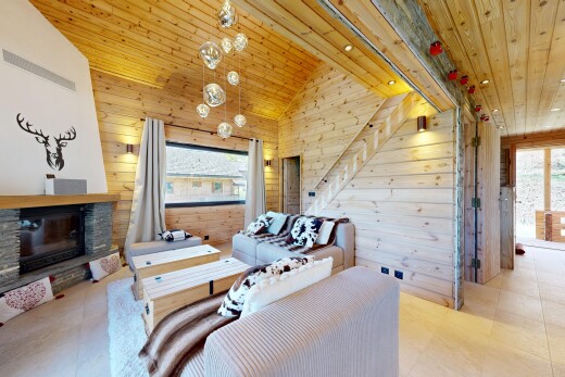 living room with a vaulted wooden ceiling, wooden walls, a stone fireplace, and plenty of natural light