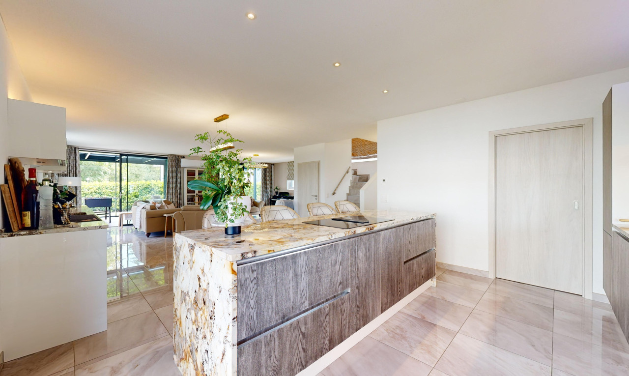 küche mit kücheninsel, stein arbeitsplatten, öffnet sich zum wohnraum, natürliches licht, und schränke mit flachen paneelen