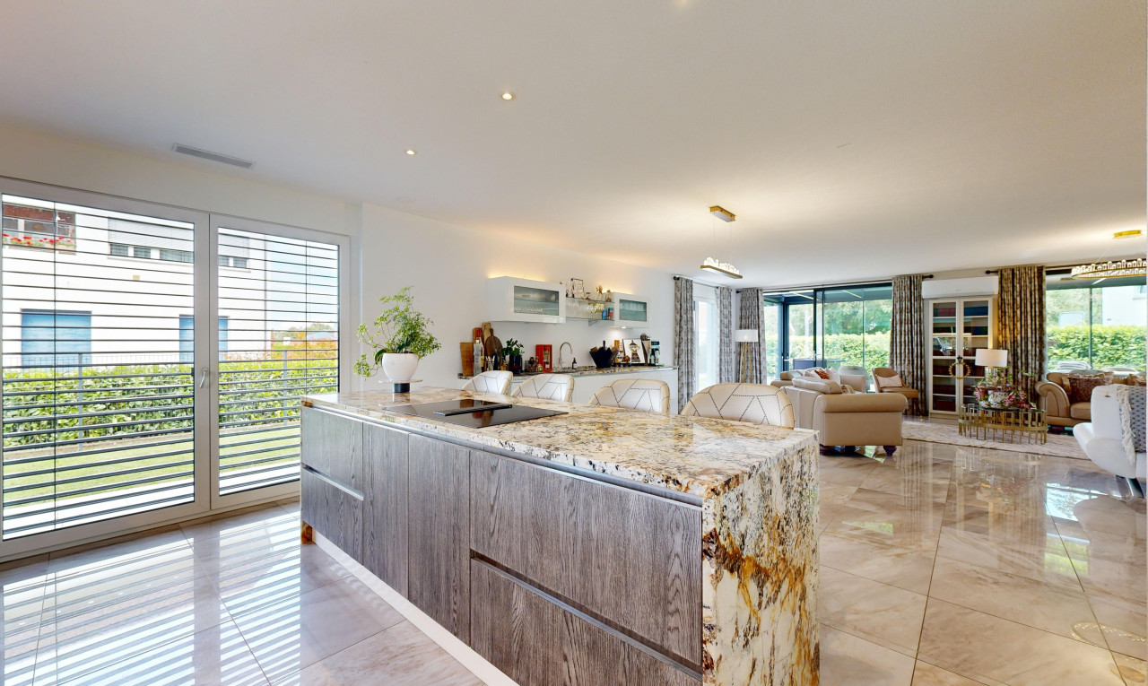 küche mit stein arbeitsplatten, öffnet sich zum wohnraum, fliesenboden, natürliches licht, und schränke mit flachen paneelen