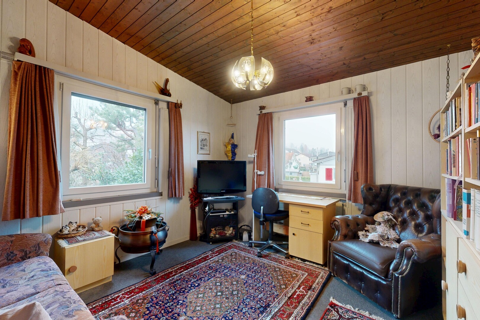 carpeted living area with wood walls, wooden ceiling, healthy amount of natural light, and a chandelier