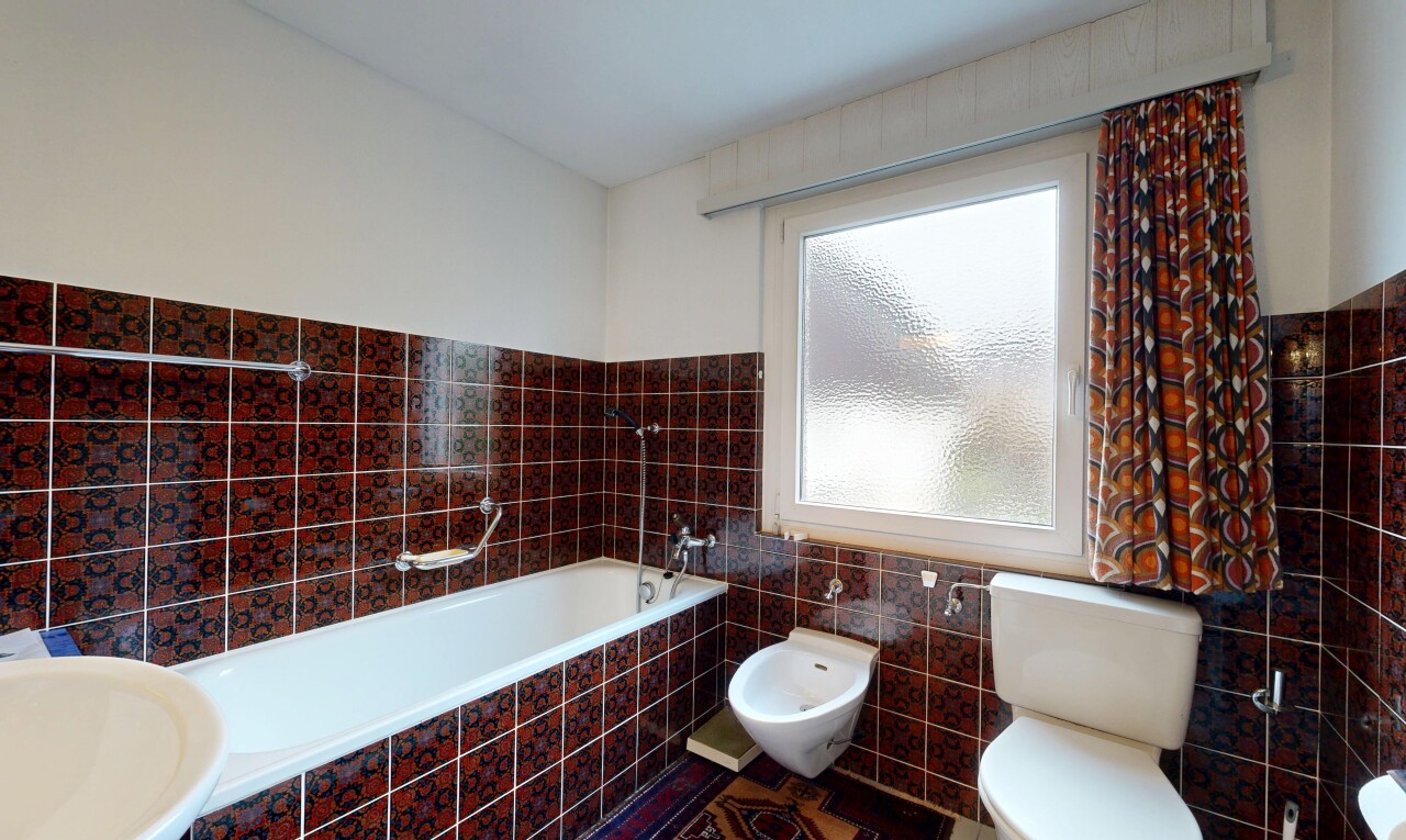 bathroom with tile walls, a garden tub, a bidet, and a wainscoted wall