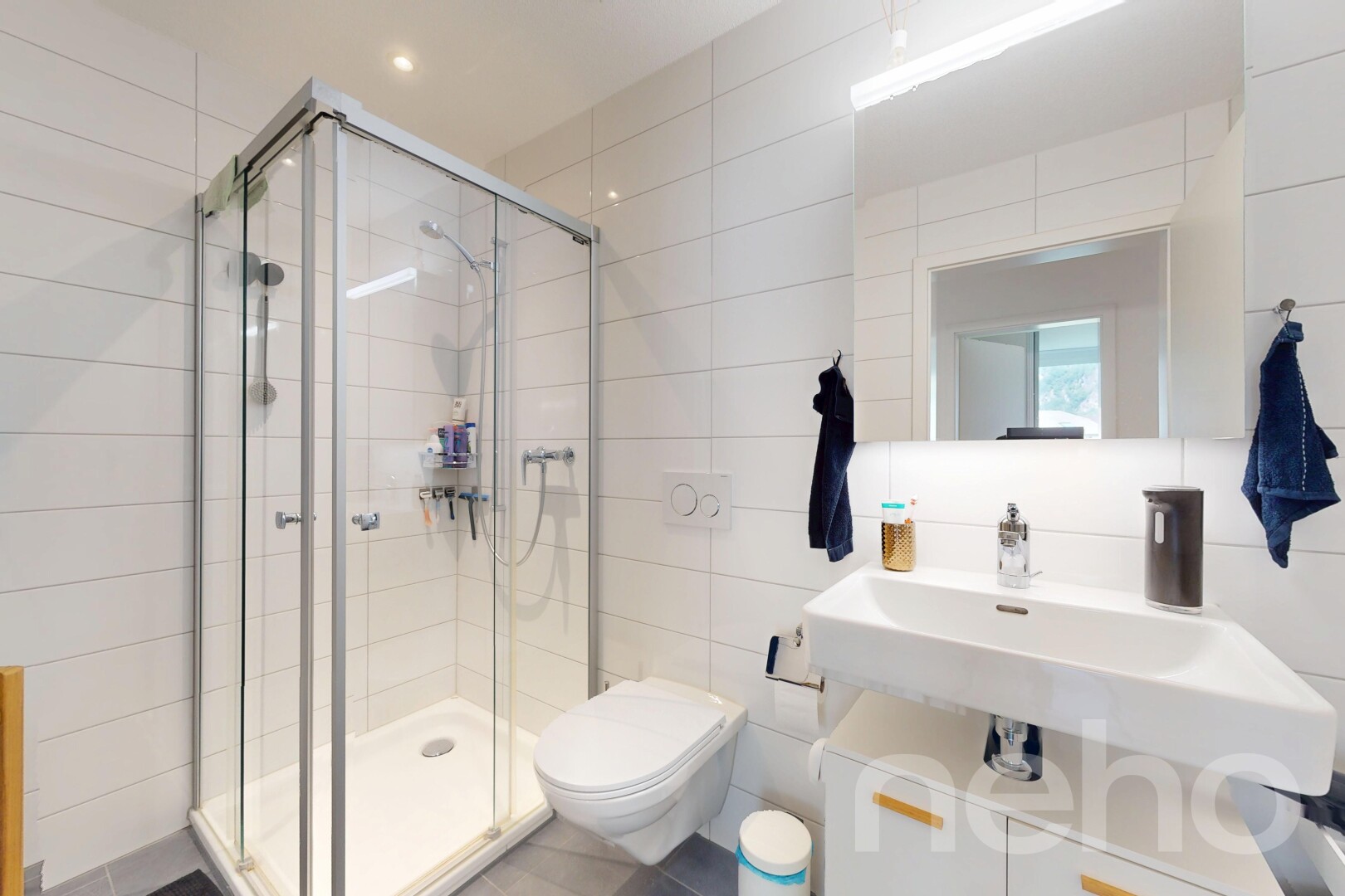 salle de bains avec tile wall, mur en carrelage, miroir, douche, et salle de bain complète