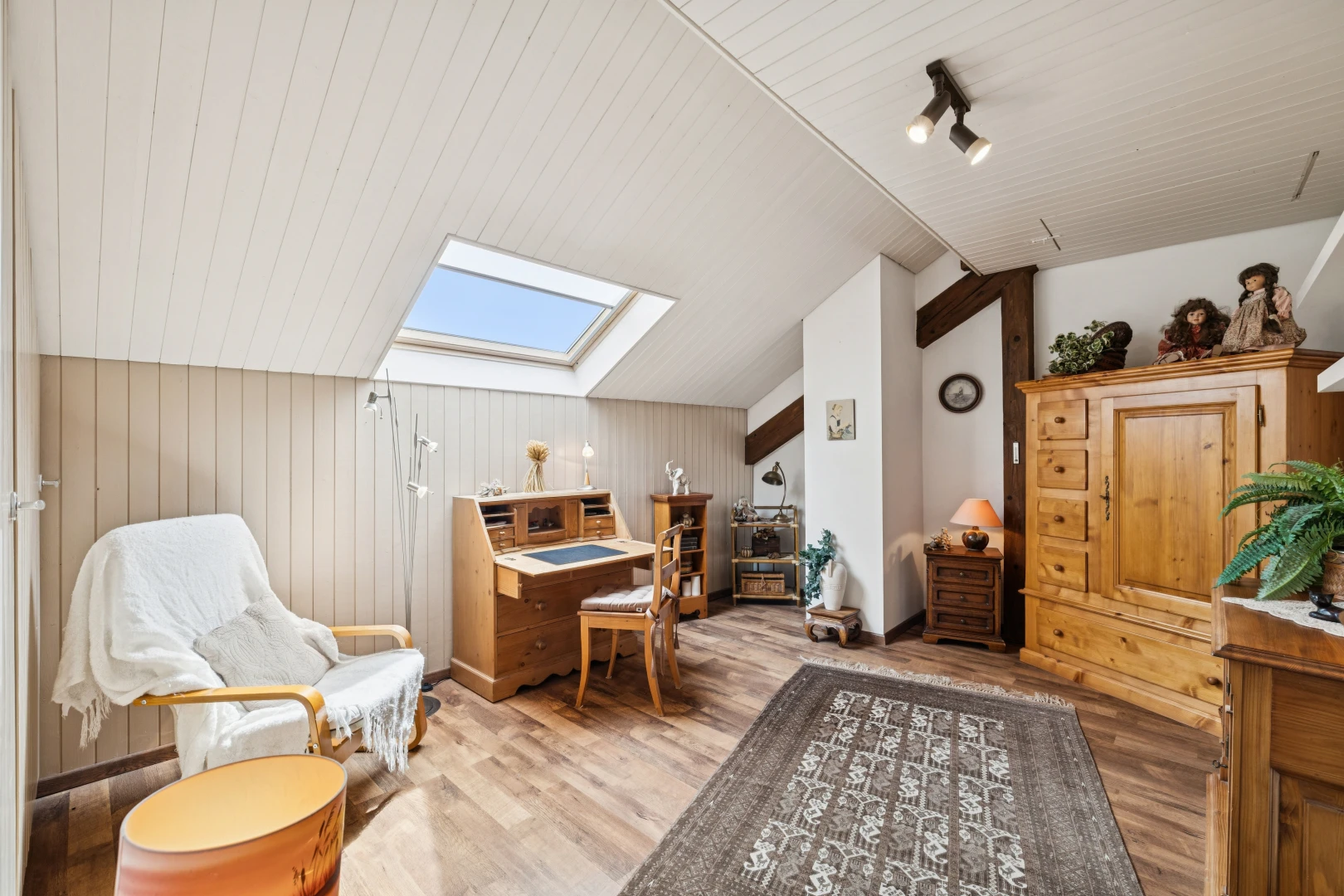salon avec éclairage sur rail, vaulted ceiling, plafond voûté, puits de lumière, et wood finish floor