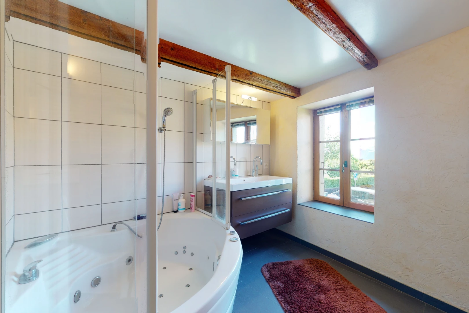 salle de bains avec lumière naturelle, baignoire, et meuble-lavabo