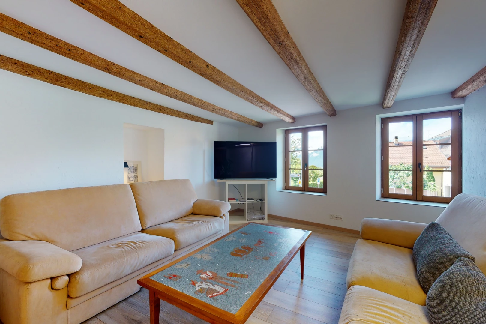 salon avec poutres apparentes, lumière naturelle, parquet, et télévision