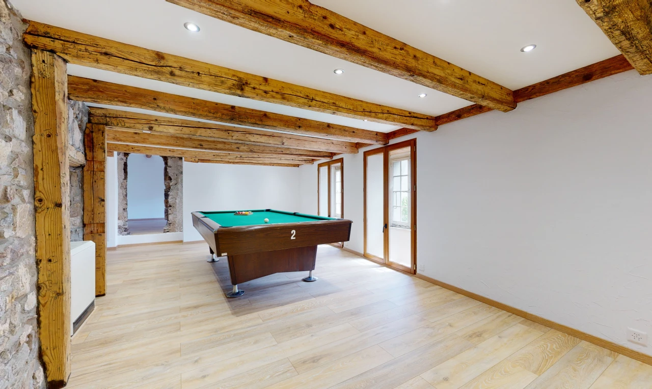salle de jeux avec poutres apparentes, lumière naturelle, et parquet