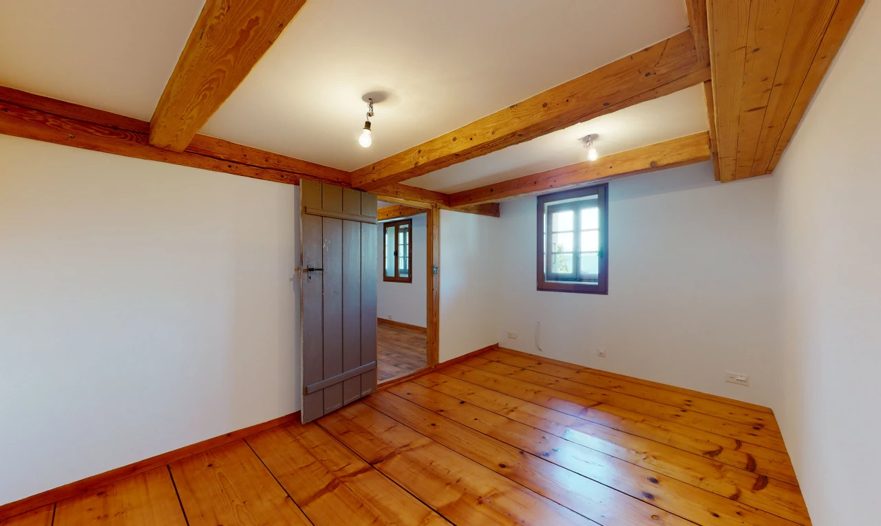 chambre vide avec parquet et poutres apparentes