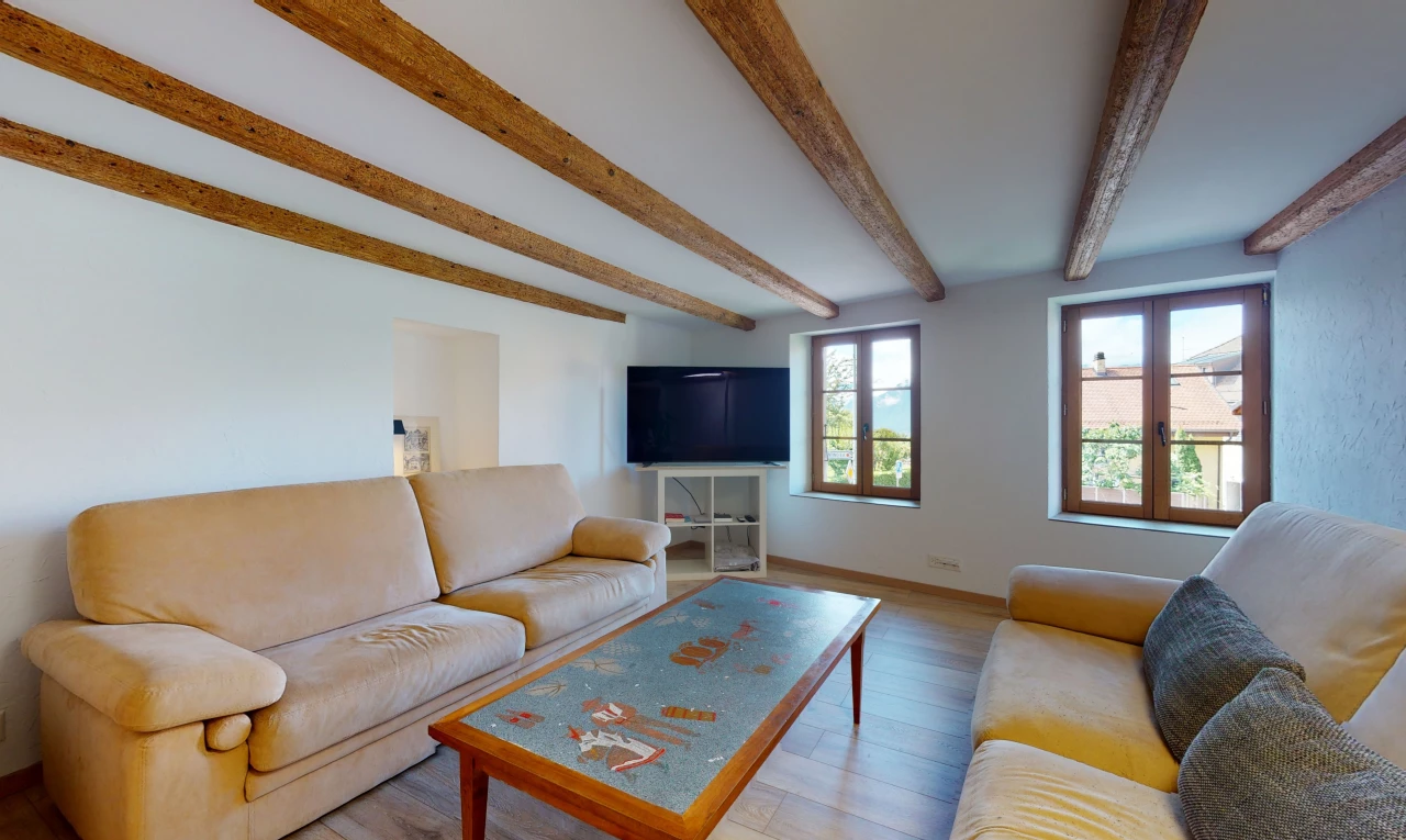 salon avec poutres apparentes, lumière naturelle, parquet, et télévision