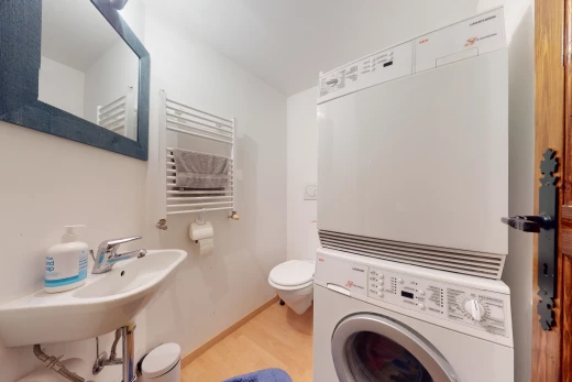 salle de bains avec parquet, radiateur, machine à laver / sèche-linge, toilette, miroir, et vasque